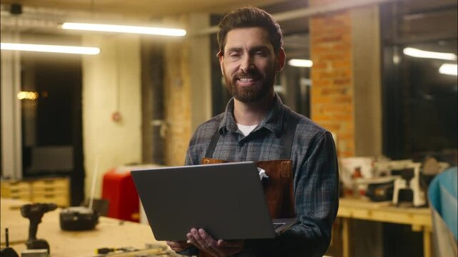 Positive Caucasian wood master man typing laptop online in workshop small business craftsman guy using computer device male joiner worker smile carpenter virtual shopping application Internet website