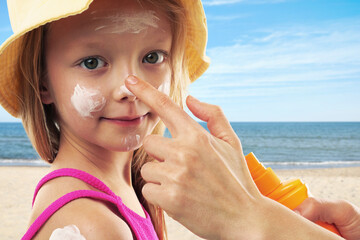 Mother applying sunscreen onto her daughter's face at beach, closeup. Sun protection while outdoor...