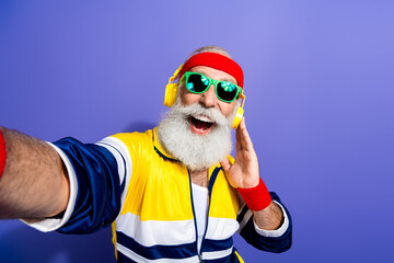 Enthusiastic senior in retro sportswear enjoying music and having fun, demonstrating active...