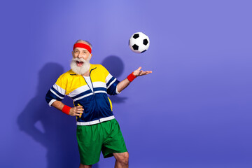 Funny sportsman in colorful retro outfit smiling while holding a soccer ball against a vibrant...