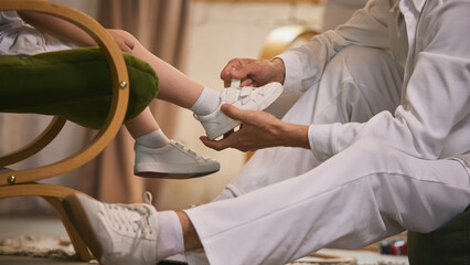 Involved fatherhood. Father helping his little child tie his shoe in warm family moment. Concept of...