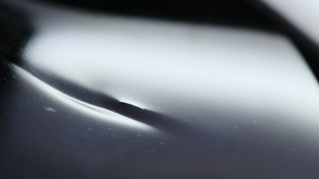 Light falls on unevenness highlighting slight damage to metal. Thin deep dent on special flat surface of clean smooth automobile body