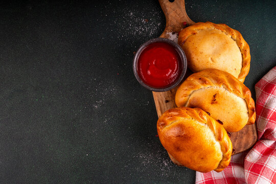 Homemade golden baked hand pies, with filling. Italian closed pizza calzone, empanadas, pierogies. Mini puff pastry or hand pies filled with sweet or savory stuffing. 