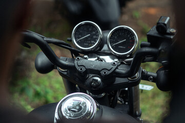 Close-up of a matte black motorcycle's handlebars, dashboard, and classic gauges, ready for the...