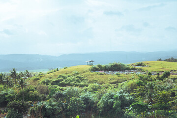 Lush Green Hills Under Overcast Sky with Distant Gazebo Structure
