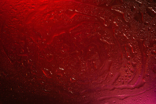 Wet glass. Drops of water on glass. Abstract red texture. Light spots