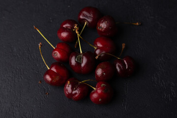 Rotten ripe cherries with mold and rotten sides on a black background. Seasonal fruits, harvest. Selective focus, close-up.