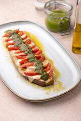 Baked eggplant with mozzarella cheese, tomatoes and pesto sauce. Traditional homemade seasonal dish. Grilled stuffed eggplant. Hearty summer dish. Selective focus, close-up.