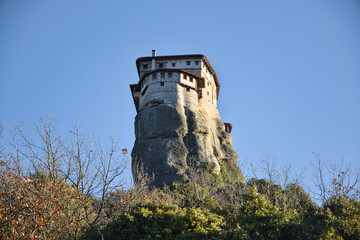 Meteora’s monasteries perch on rocky cliffs, lit by soft afternoon winter sun, blending nature...