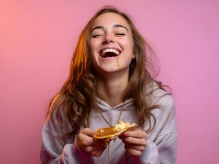 Joyful young woman enjoying a sweet treat, smiling with honey dripping, against a vibrant pink backdrop