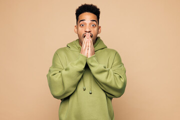 Young shocked surprised man of African American ethnicity he wear green hoodie casual clothes cover...