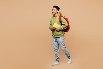 Full body side view young smart boy student wearing green casual clothes backpack bag hold books...