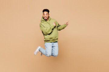 Full body young man of African American ethnicity wear green hoodie casual clothes jump high point...