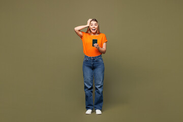 Full body young shocked surprised happy woman she wears orange t-shirt casual clothes hold in hand...