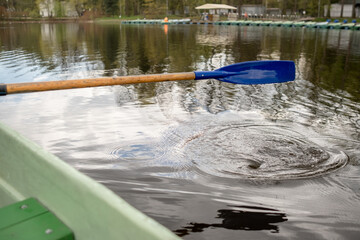 A person is rowing on a calm lake, creating ripples as the oar enters the water, surrounded by...