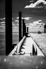 Perspective black and white photo of an industrial harbor wall with cloudy sky, taken on the south...