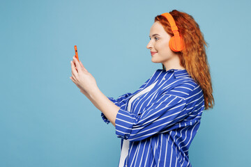Side view young ginger woman she wear shirt t-shirt casual clothes listen to music in headphones...