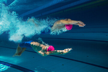 Collage with swimmers in dramatic underwater scene, moving in perfect opposition with explosive...