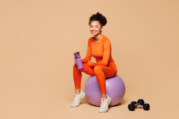 Full body young fitness trainer instructor sporty woman sportsman wear orange clothes spend time in...