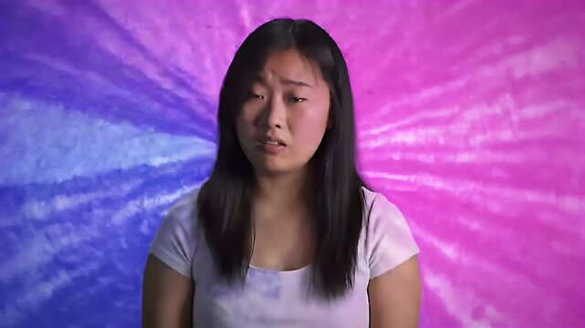 Woman stands with a concerned expression before a colorful backdrop
