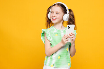 Little kid child girl 8-9 years old wears green t-shirt listen to music in headphones use mobile...