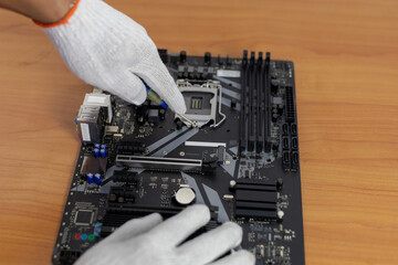  A close-up shot of gloved hands using a tool to work on the CPU (Central Processing Unit) socket...