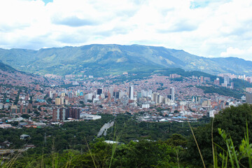photograph taken of the city of Medellin from one of its hills with a view towards its high and low-income neighborhoods. city in the middle of a valley and surrounded by mountains, and in the backgro