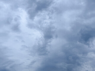 Stormy sky with dark, snowy clouds on a spring day. Clouds are floating across the sky. Dark blue clouds swiftly floating across blue sky. Storm dramatic clouds are floating across the sky. Hurricane.