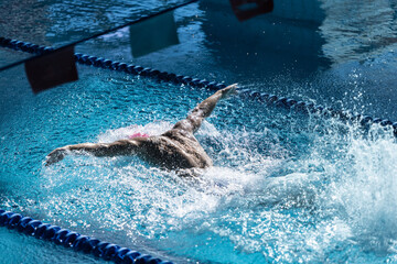 Energy. Male swimmer in a pink cap is shown mid-butterfly stroke, with visible muscle definition...