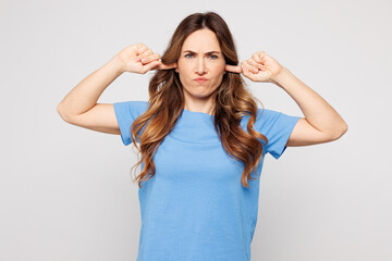 Young sad Caucasian woman wear blue t-shirt casual clothes cover ears with hands fingers do not...