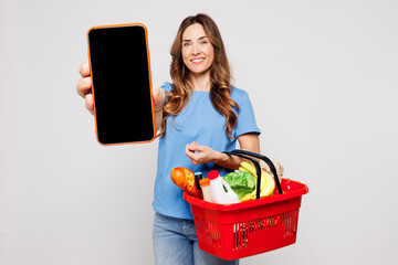 Young woman wearing blue t-shirt casual clothes hold basket bag for takeaway with food products use...