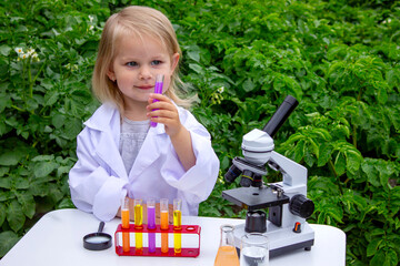 A little girl conducts experiments using test tubes, reagents, and a microscope.