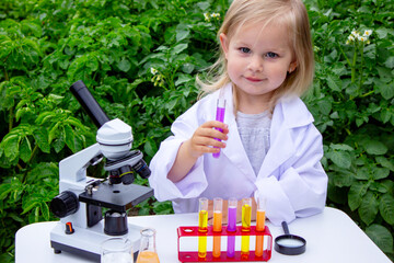 A little girl conducts experiments using test tubes, reagents, and a microscope.