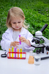 A little girl conducts experiments using test tubes, reagents, and a microscope.