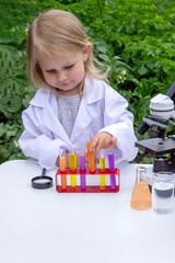 A little girl conducts experiments using test tubes, reagents, and a microscope.