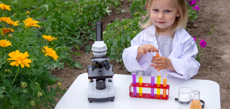 A little girl conducts experiments using test tubes, reagents, and a microscope.