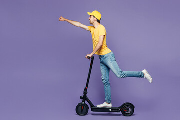 Full body side view young delivery guy employee man he wear yellow cap t-shirt uniform workwear...