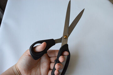 hand holding large metal scissors with black handle  ideal for themes like sewing, crafting,...