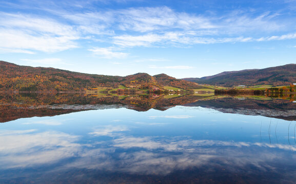 Fototapeta A tranquil mountain lake surrounded by hills reflecting clear skies