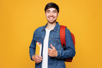 Young smiling happy smart boy student he wears jeans casual clothes backpack bag hold books showing...