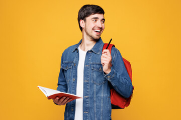 Young happy boy student he wear jeans casual clothes backpack bag hold books write down notes in...