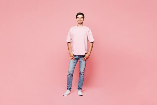 Full body young smiling happy cheerful fun confident Caucasian man he wear t-shirt casual clothes stand look camera isolated on plain pastel light pink background studio portrait. Lifestyle concept