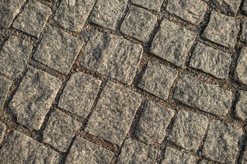 Close-up view of textured cobblestones forming a unique pattern on a city street, illustrating...