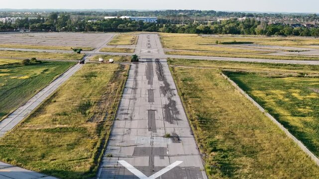 Close, low-level aerial flying along decommissioned Buttonville Airport runway toward nearby industrial buildings during daylight