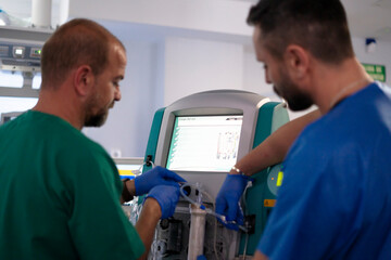 Two surgeons preparing dialysis machine in operating room
