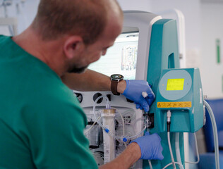 Doctor setting up dialysis machine in hospital room