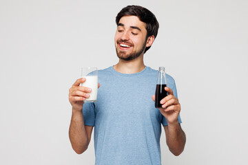 Young man he wear blue t-shirt casual clothes hold glass of milk choose between bottle of cola...