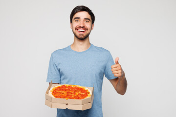 Young man he wear blue t-shirt casual clothes holding italian pizza in cardboard flatbox show thumb...
