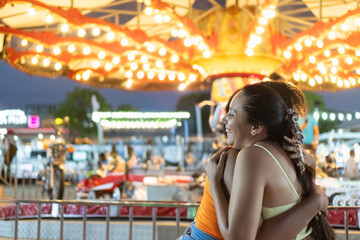 Friends embracing joyfully at a vibrant carnival