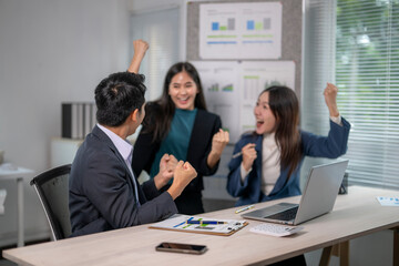 Three people are celebrating in a business setting